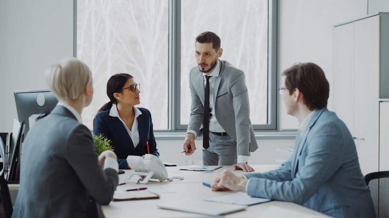 Professionals engaged in a serious business discussion in a bright office environment.